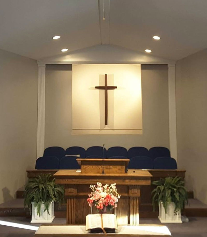 Púlpito de madera y cruz iluminada en el santuario de la Iglesia Bautista Madison